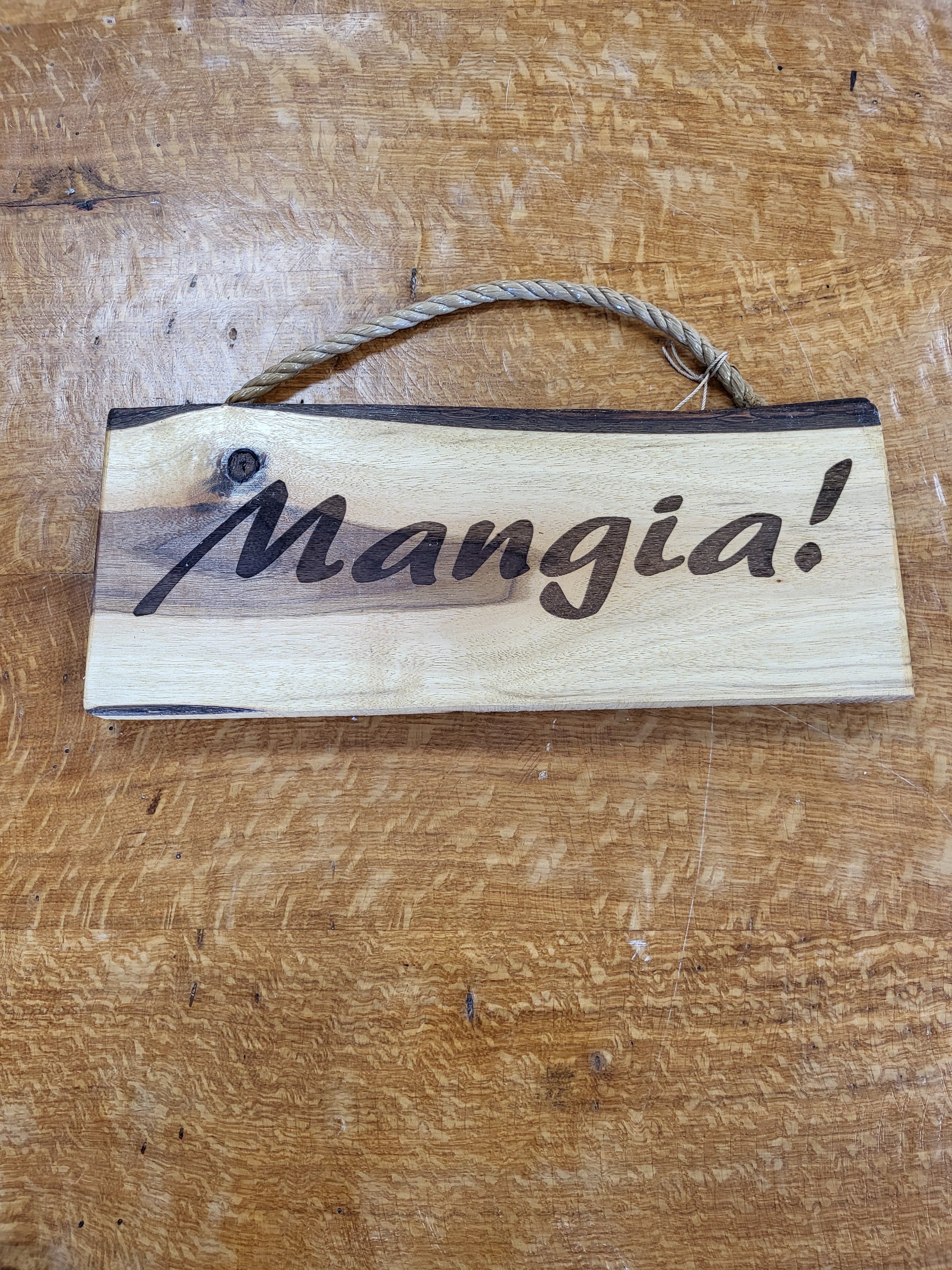 Wooden sign with 'Mangia!' engraved on a wooden surface