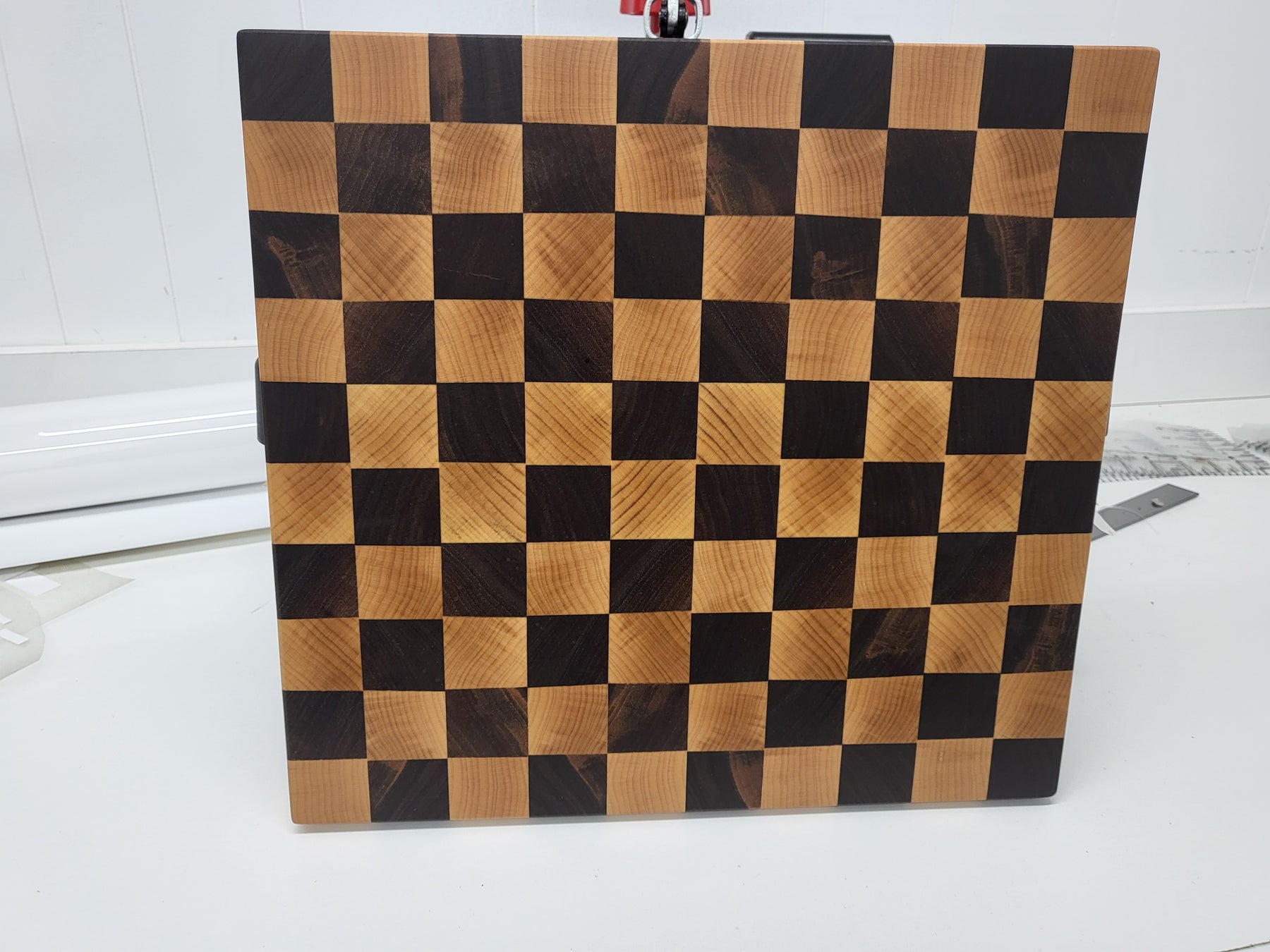 Checkered wooden cutting board on a white surface